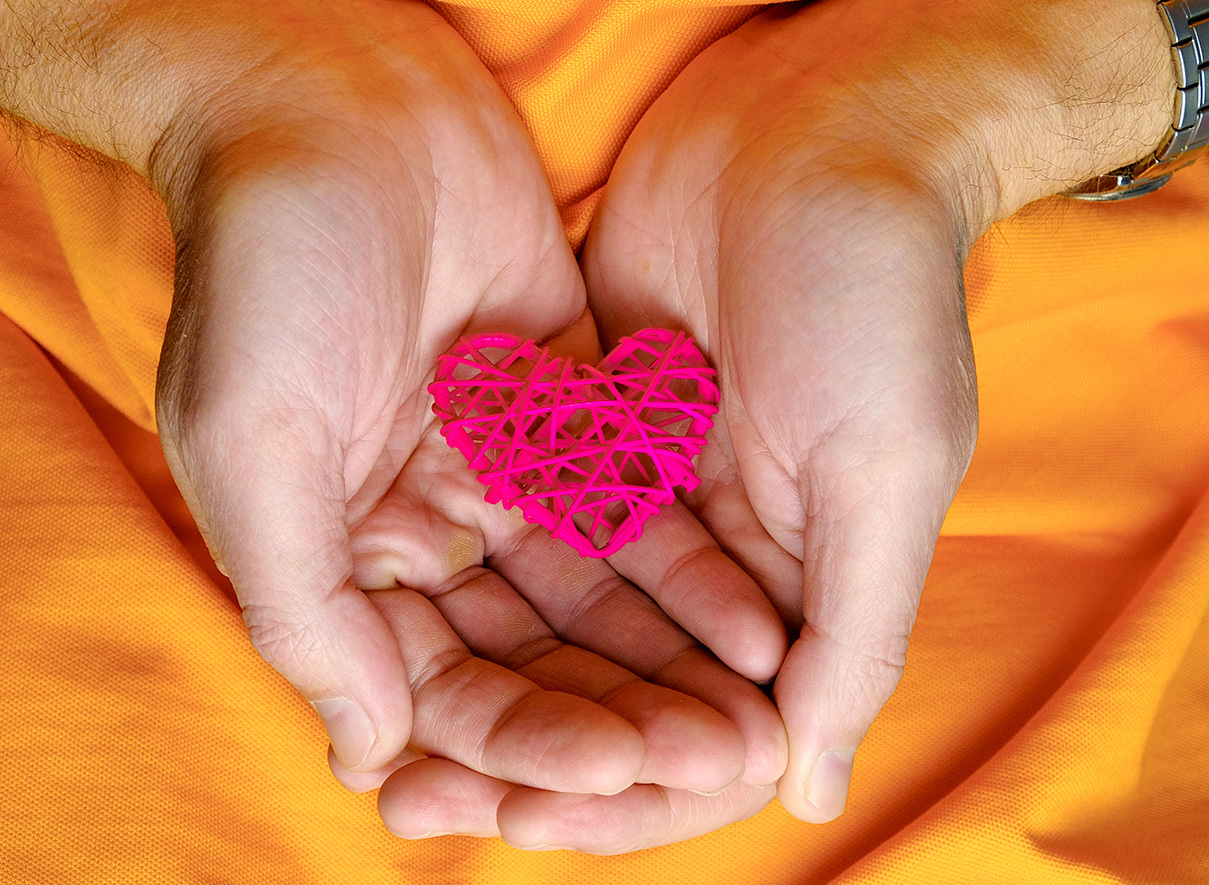 Two hands holding a small, crafted heart.