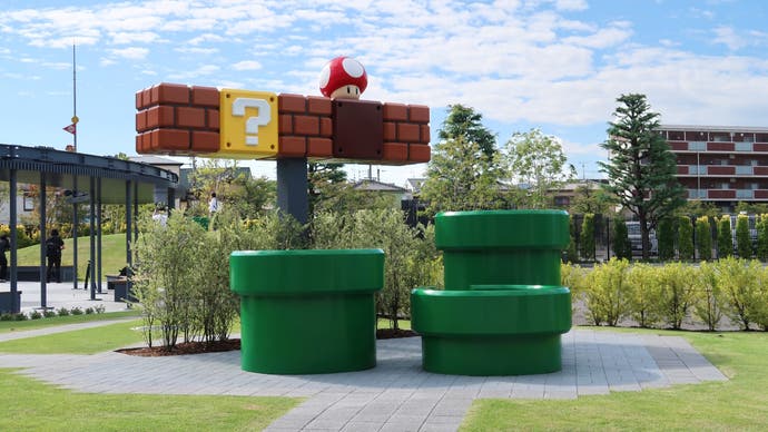 A photograph of three Mario pipes and a row of blocks in the outdoor courtyard of the Nintendo Museum.