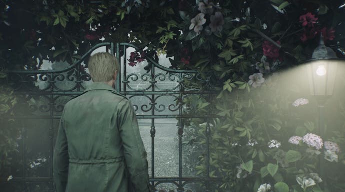 A screenshot from Silent Hill 2 Remake: James stands before a gate in a beautiful, if foggy, garden.