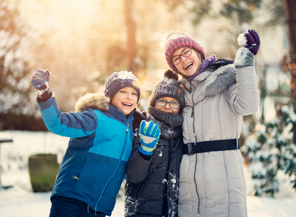 A pair of red snow-gloves holding a snowball shaped like a heart.